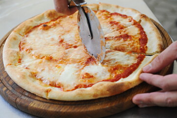 Almaty, Kazakhstan - 05.29.2021 : The master cuts the finished pizza into pieces