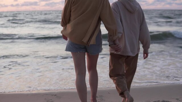 Women in love go by the hands to the sea and raise their hands at sunset. lesbians in the evening walk by the sea.