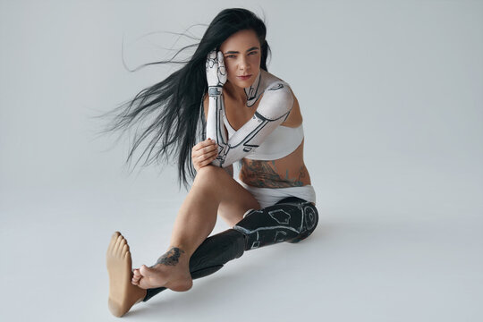 Horizontal view of a brunette tattooed girl with cyborg body art and prothesis leg
