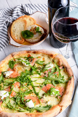 Pizza with mozzarella, salmon slices, fresh arugula. Served with baked cheese camembert and red wine. Italian cuisine