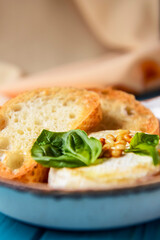 Baked camembert with sauce and toast served in a white bowl over beige cloth background. Delicious dinner idea