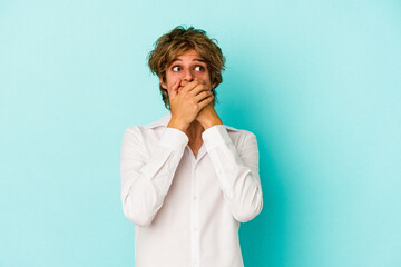 Young caucasian man with make up isolated on blue background  thoughtful looking to a copy space covering mouth with hand.