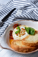 Baked camembert with sauce and toast served in a white bowl. Delicious dinner idea