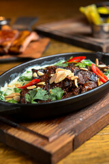 Meat with vegetables served with sauce in a pot over rustic wooden background. Rustic style dinner