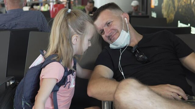 A Dad And A Young Daughter Are Waiting For A Plane In The Waiting Room At The Airport During The Coronavirus Pandemic. Masked Man