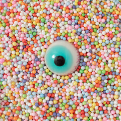 Eyeball on colorful candy pellets. Minimal Halloween concept. Fun holiday party food idea.