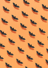 Fototapeta na wymiar Halloween pattern made of flying bats with sunlight shadows against an orange background. Creative scary holiday concept.