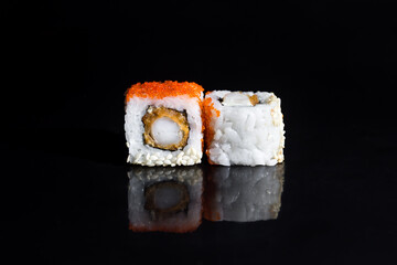 Close-up of delicious sushi rolls on a black glossy Board. Horizontal photo of food on a black background.