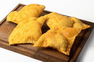 Homemade chebureks with meat and onion on wooden board over white background.