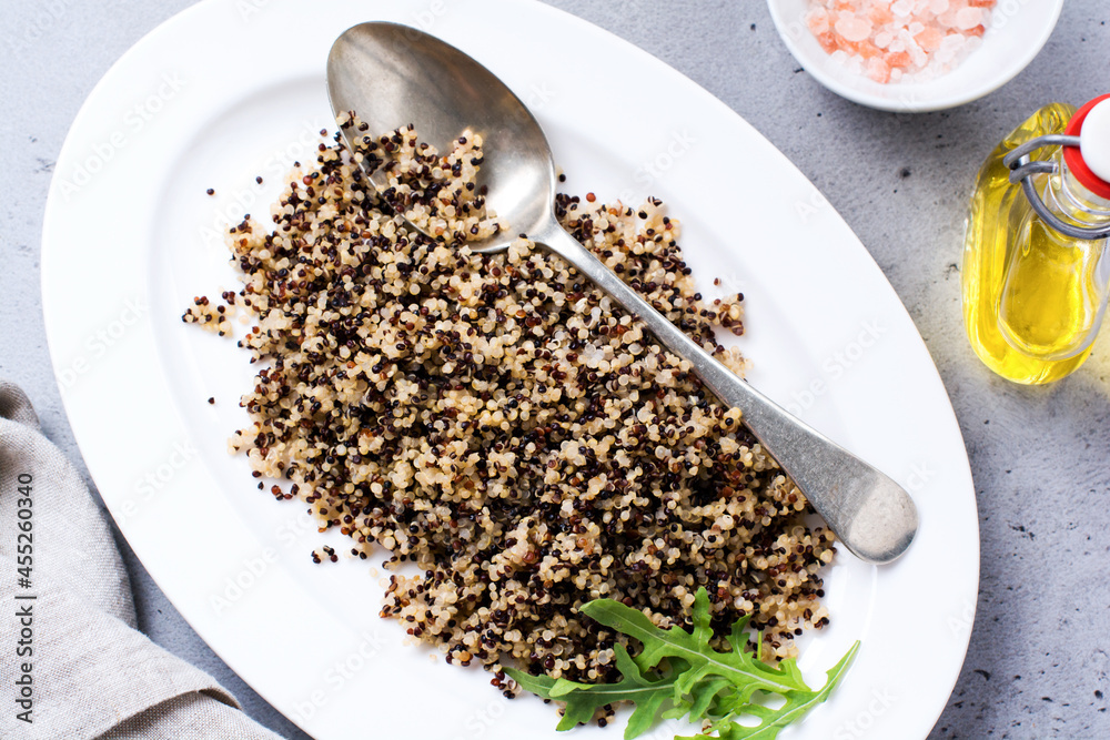 Wall mural cooked white, red and black quinoa in white plate on grey rustic background, top view, place for tex