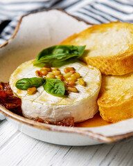Baked camembert with sauce and toast served in a white bowl. Delicious dinner idea