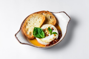 Baked camembert with sauce and toast served in a white bowl over white background. Delicious dinner idea
