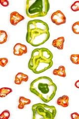 Green and red peppers, cut into round slices, lie on a white background