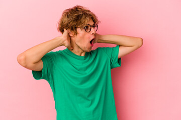 Young caucasian man with make up isolated on pink background screaming, very excited, passionate,...