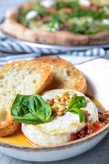 Baked camembert with sauce and toast served in a white bowl. Delicious dinner idea