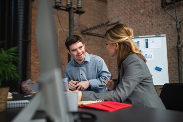 Happy down syndrome man with businesswoman colleague working in office, social inclusion and...