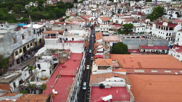 Low aerial sweep over the city of Taxco de Alarcon in Mexico with narrow streets and terracotta rooftops.