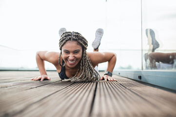 Young woman doing exercise and looking at camera outdoors on terrace, sport and healthy lifestyle concept.