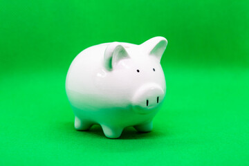White piggy Bank stand on a green background.