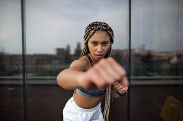 Young woman doing exercise and looking at camera outdoors on terrace, sport and healthy lifestyle...