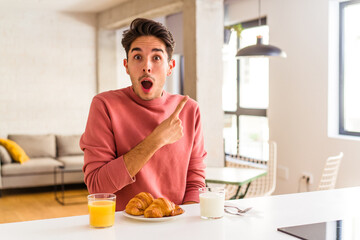 Fototapeta na wymiar Young mixed race man having breakfast in a kitchen on the morning pointing to the side