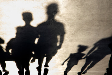 Blurry shadow silhouette of  families walking on a promenade on a summer day