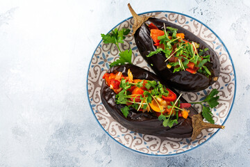 Baked stuffed eggplant with different vegetables, tomato, pepper, onion and parsley on gray stone or concrete table background. Top view