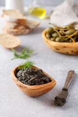 Black Tapenade or tapas, traditional Provence dish or dip with olives and basil on an old wooden table background. Selective focus. Top view