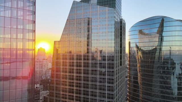 Cinematic close up aerial pan shot capturing reflective mirror glass window facade skyscrapers in downtown Buenos Aires central business district during sunset golden hours.