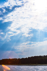 The rays of God in the river landscape. The sun's rays shine through the clouds over the water surface and the shore. Copy space