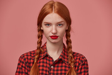 close up of young ginger female looks thoughtfully looks into camera, keeps calm and positive.