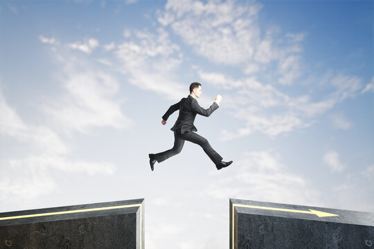 Side View Of Businessman Jumping Over Gap On Sky Background With Mock Up Lace. Challenge And Success Concept.