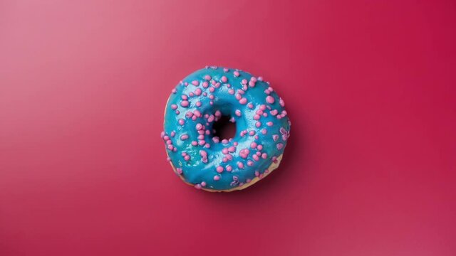 Blue Frosting Donut With Sprinkles At Pink Background. Sweet Dessert. Bakery And Food Concept. Isolated Donut Rotates On Pink Background. 4K, UHD