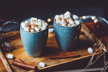 Hot chocolate with marshmallow and cinnamon in blue ceramic cups on a table. The concept of cosy holidays and New Year.