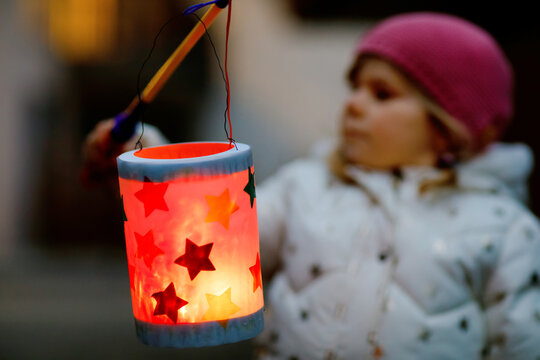 Close-up of little kid girl holding selfmade lanterns with candle for St. Martin procession. Healthy toddler child happy about children and family parade in kindergarten. German tradition Martinsumzug
