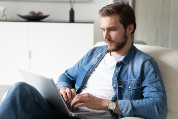 Handsome man using laptop computer at home. Online shopping, home work, freelance, online learning, studying concept