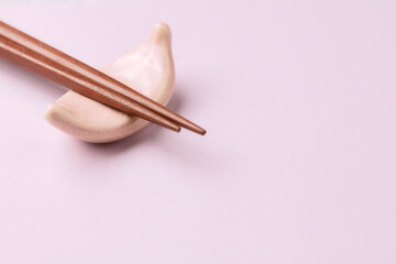 Wooden chopsticks and chopstick rest on bright paper background. Close up. Copy space. 