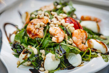 Fresh greens salad with seafood poured with sauce. Close-up