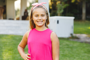 Portrait of smiling caucasian girl outside house looking at camera in garden