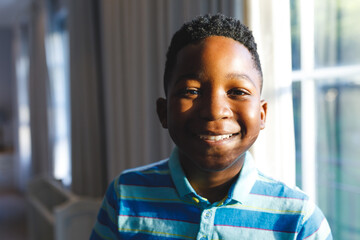 Portrait of african american boy looking at camera and smiling in living room
