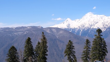 picturesque landscape of snow-capped mountains with white clouds on a blue sky on a sunny day at Krasnaya Polyana in Sochi, Russia