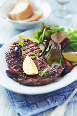 Grilled pork steak with fresh salad. Bright wooden background. Close up. 