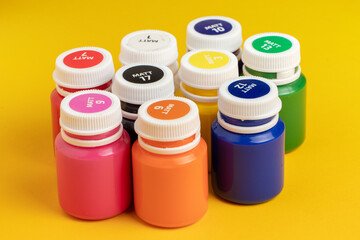 Bottles with multicolored paints on yellow background