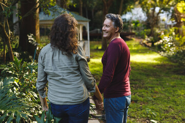 Happy senior caucasian couple holding hands in sunny garden