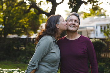 Fototapeta premium Happy senior caucasian couple kissing and smiling in garden