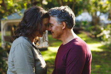 Happy senior caucasian couple embracing and smiling in sunny garden