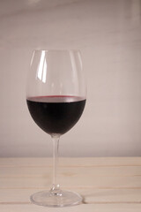 Crystal goblet containing red wine on a neutral white background. Available space to write.