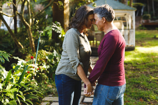 Happy senior caucasian couple holding hands in sunny garden
