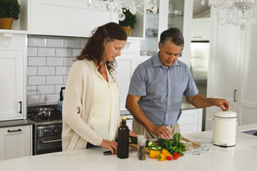 Senior caucasian couple in modern kitchen, cooking together composting organic waste