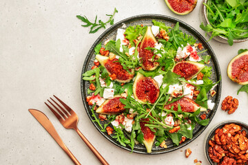 Sweet fig salad with soft goat cheese, walnuts, arugula and jam dressing on white background, top view, copy space